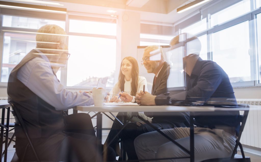 Colleagues collaborating at a conference table in a sunlit office.