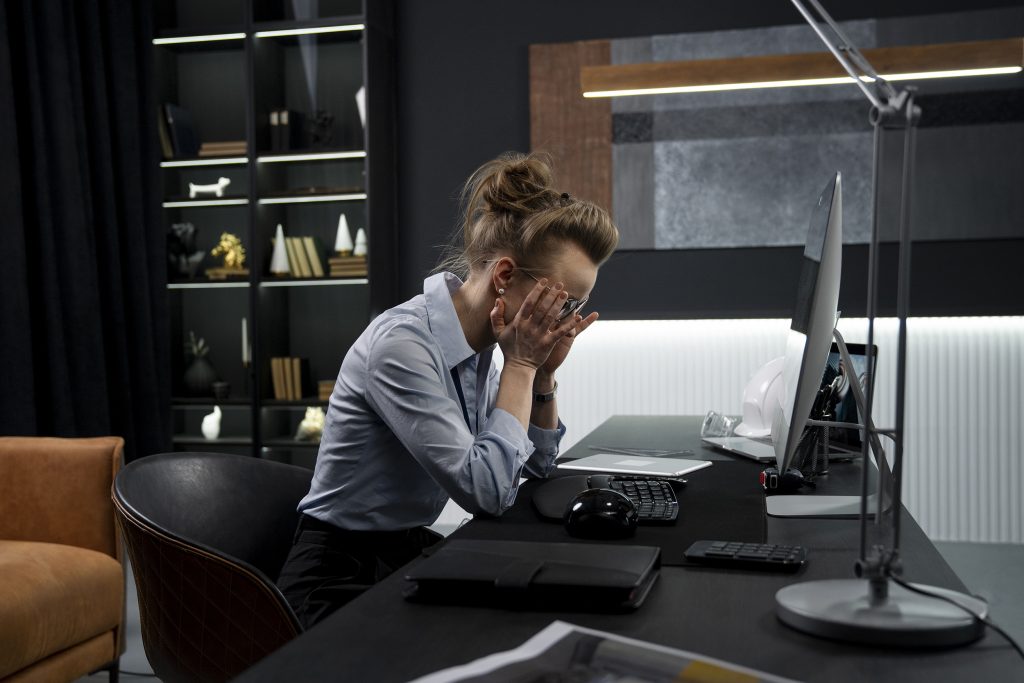 Businessperson working late at a desk under focused lighting.