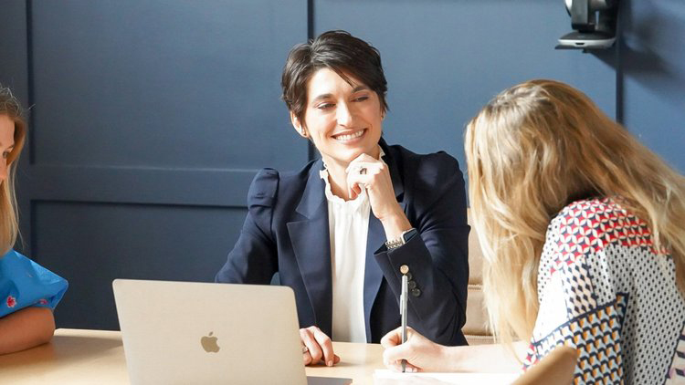 Two coworkers collaborating at a laptop during a meeting.
