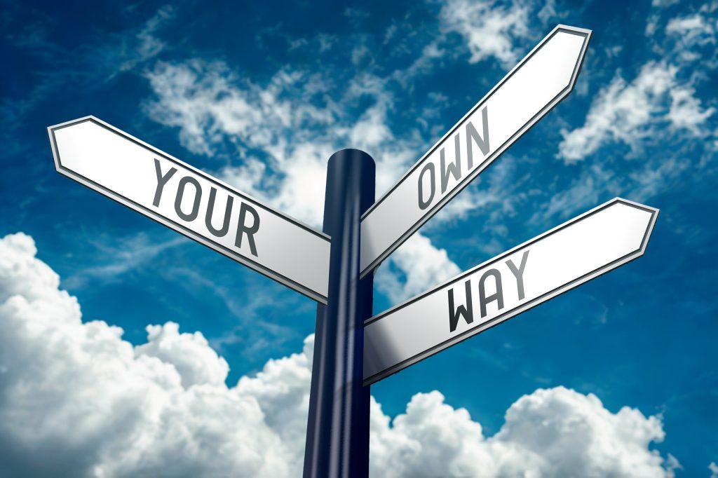 Signpost with arrows labeled “Your Way” and “Join” in front of a cloudy sky.